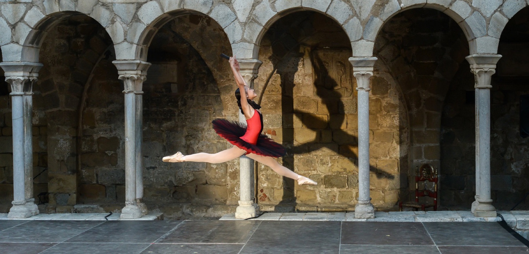 Ballarina en arabesc entre les arcades d’un claustre