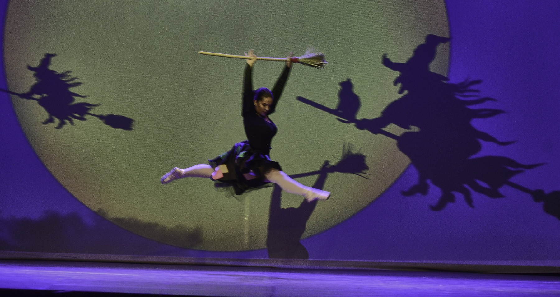 Coreografia de bruixes amb escombres davant d’una lluna